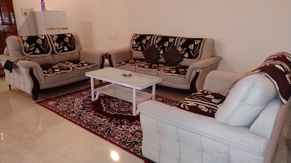 A living room with two sofas, a coffee table, and a patterned rug. - SK Brownstone Villa Mahableshwar Luxurious 5-bedroom villa with AC, WiFi (Mahabaleshwar)