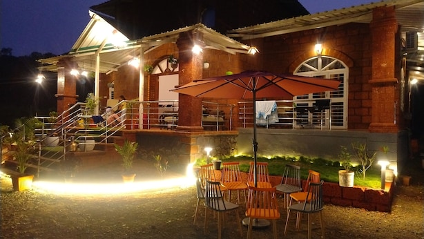 A building with a covered outdoor area, outdoor seating, and a staircase leading to an upper level. - SK Brownstone Villa Mahableshwar Luxurious 5-bedroom villa with AC, WiFi (Mahabaleshwar)