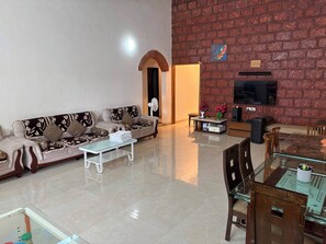 A living room with a sofa, coffee table, TV, and a brick wall.