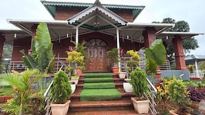 A building with a traditional architectural style, featuring a wooden door and a covered entrance with steps leading up to it. - SK Brownstone Villa Mahableshwar Luxurious 5-bedroom villa with AC, WiFi (Mahabaleshwar)