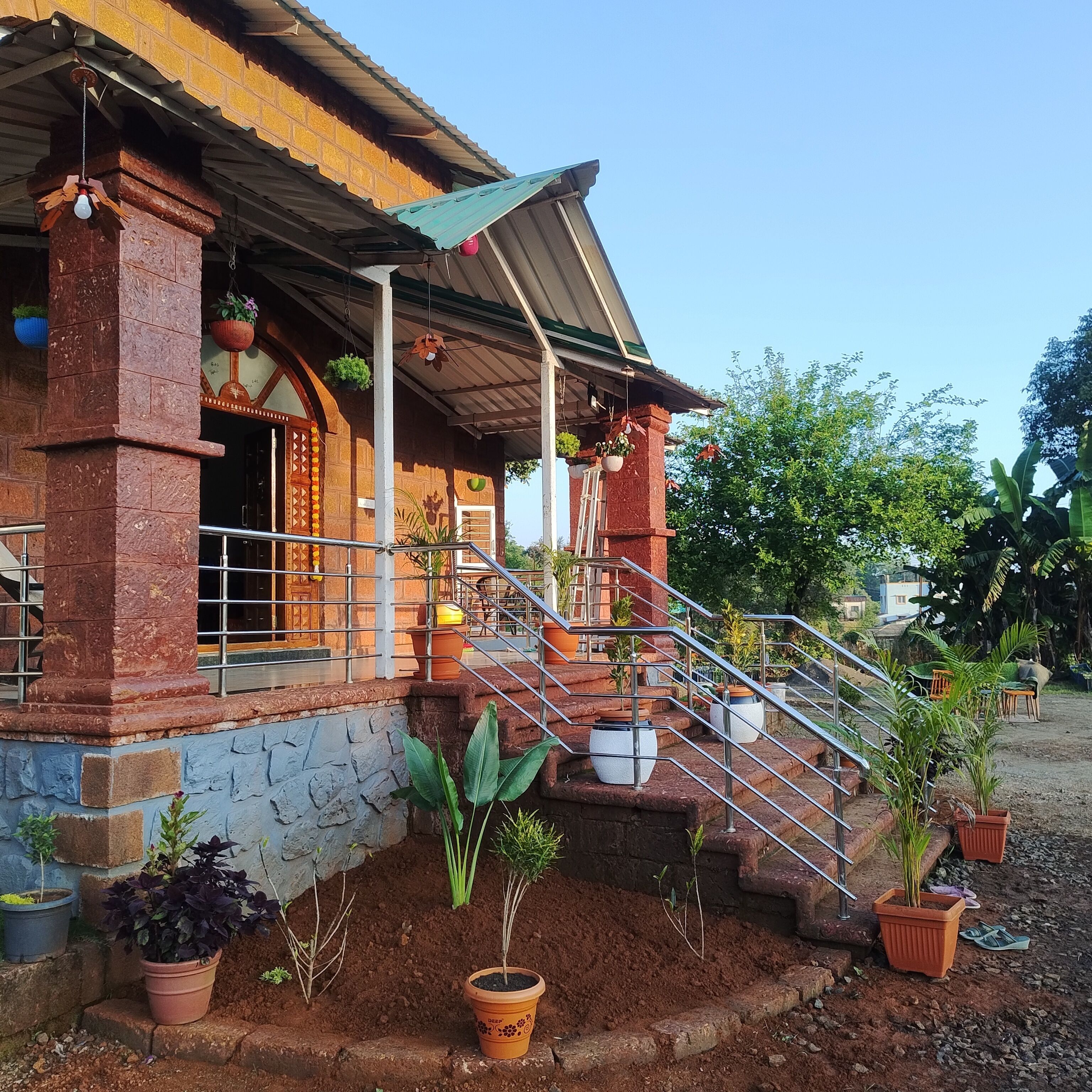 Uma casa com varanda, degraus e plantas em vasos.