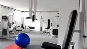 Et fitnessrum med forskellig træningsudstyr, en blå træningsbold og en rød måtte.