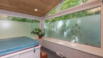 Une pièce avec un plafond en bois, une grande fenêtre à vitres dépolies, un banc bleu et une plante en pot.