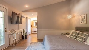 Une chambre à coucher avec un lit, une table de chevet et un téléviseur fixé au mur.