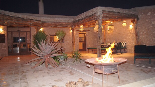 An outdoor patio with a fire pit, stone walls, and a rustic wooden pergola.