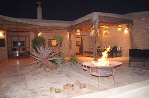 An outdoor patio with a fire pit, stone walls, and a rustic wooden pergola. - MAROC WEEKEND (Sidi Kaouki)