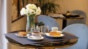 A table with a pastry, a cup of coffee, a glass of water, and a vase of flowers. - Palazzo Paisiello - Luxury Rooms Lecce (Lecce)