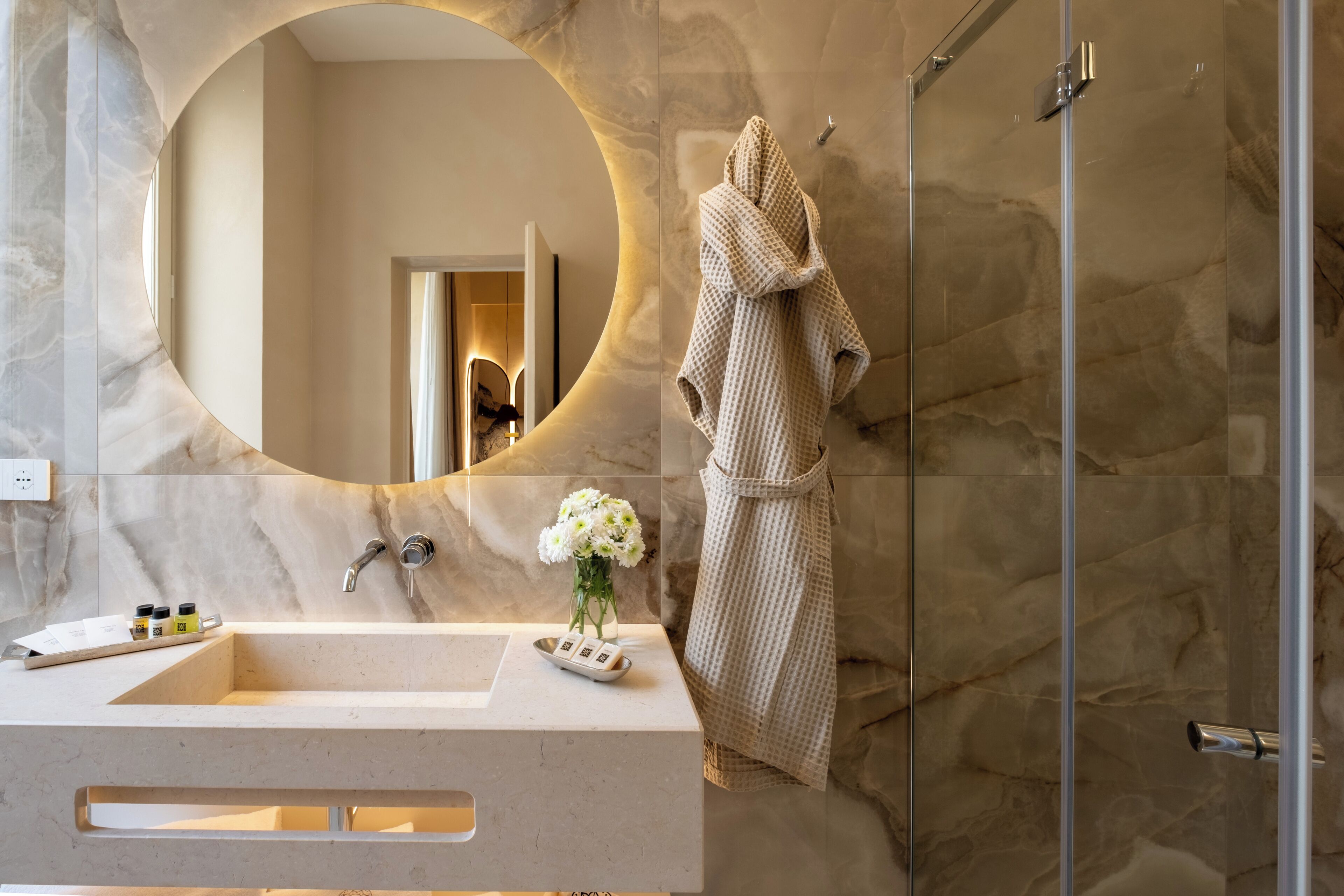 Une salle de bain avec un meuble-lavabo en marbre, un grand miroir, une cabine de douche en verre et une serviette accrochée au mur.