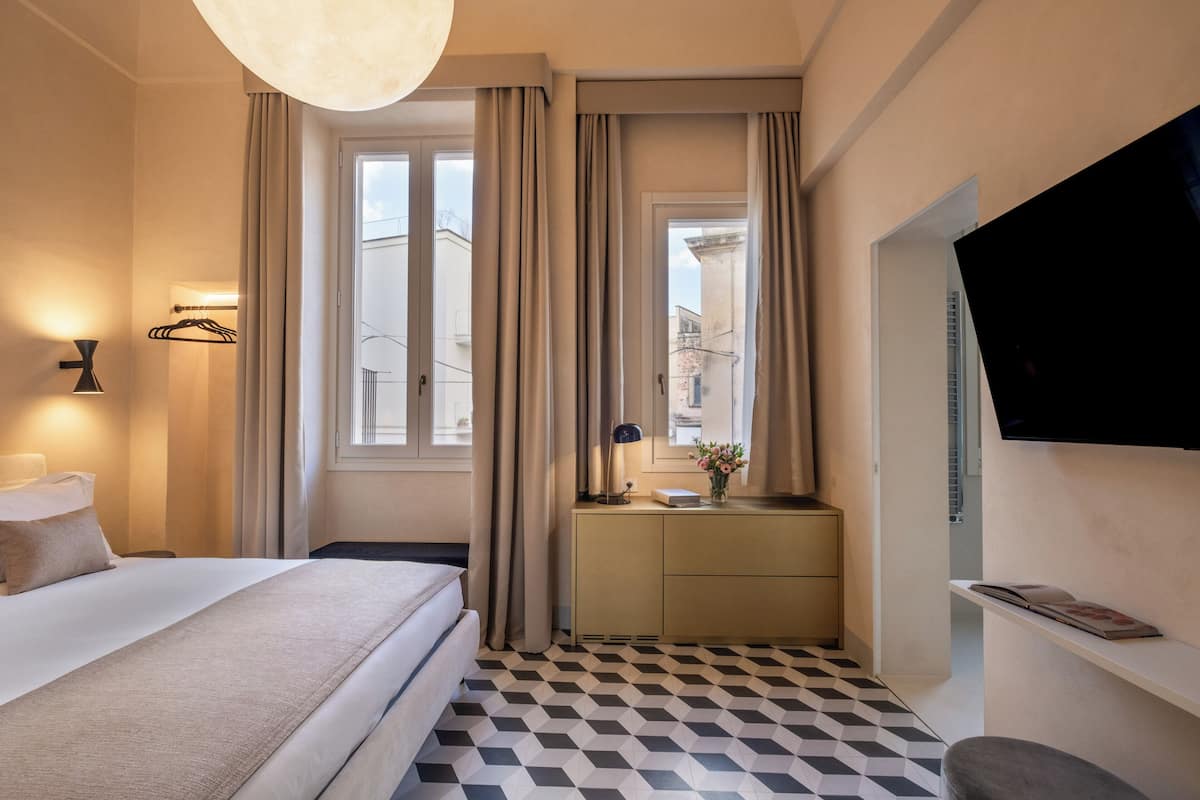 Une chambre d’hôtel équipée d’un lit, d’une table de chevet, d’une lampe, d’une télévision et d’un comptoir d’enregistrement.