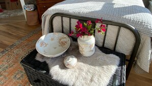A bedroom with a bed, a dresser, a basket with a bowl and a vase with flowers, and a rug. - Charming 2-bedroom, 2.5 bath Over-water House on Secluded Beach! (Boca Chica)