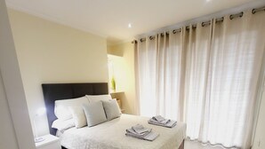 A modern bedroom with a large bed, white curtains, and a bedside lamp. - Casa Marcelino by Madeira Real (Calheta (Madeira))