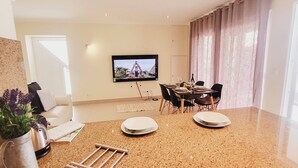 A modern kitchen with granite countertops, a dining area with a table and chairs, a flat-screen TV mounted on the wall, and a potted plant on the counter. - Casa Marcelino by Madeira Real (Calheta (Madeira))