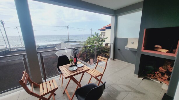 A balcony with a table and chairs, a small plant, and a view of the sea. - Casa Marcelino by Madeira Real (Calheta (Madeira))