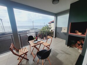A balcony with a table and chairs, a small plant, and a view of the sea. - Casa Marcelino by Madeira Real (Calheta (Madeira))