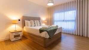 A modern bedroom with a wooden bed, bedside tables, and a large window with curtains. - Conchas do Funchal by Madeira Real (Funchal)