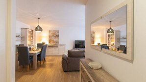 A modern living room with a dining area, a sofa, a TV, and a large mirror. - Conchas do Funchal by Madeira Real (Funchal)