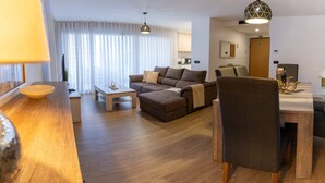 A modern living room with a sofa, ottoman, and a dining area with a table and chairs. - Conchas do Funchal by Madeira Real (Funchal)