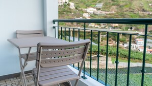 En balkon med bord og stole, der giver udsigt over en bakke med huse.