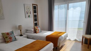 Une chambre d’hôtel avec deux lits, une table de chevet, une lampe, un attrape-rêves et une vue sur l’extérieur.