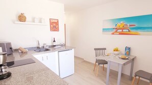 Een moderne keuken met een inbouwkoelkast, een koffiehoek en een eethoek met een tafel en stoelen.