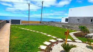 A well-maintained outdoor area with a grassy lawn, stepping stones, and a palm tree. - Studio Theo Vista Montanha (Calheta (Madeira))