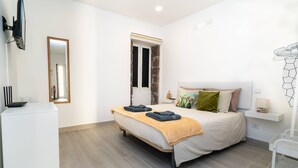 A bedroom with a bed, a mirror, a TV, and a small white cabinet. - Studio Pedro Vista Mar (Calheta (Madeira))