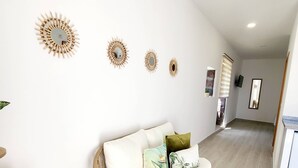 A modern living room with a curved sofa, a small wooden side table, and a potted plant. - Studio Pedro Vista Mar (Calheta (Madeira))