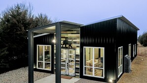 A compact, modern house with a black exterior and large windows.
