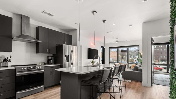 A modern kitchen with a central island, stainless steel appliances, and a dining area with bar stools.