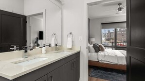 A modern bathroom with dual sinks, a large mirror, and a dark-toned wardrobe.