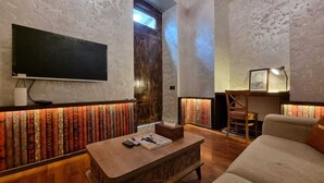 A cozy living room with a flat-screen TV, a wooden coffee table, a sofa, and a patterned wall. - Apartments History 1870 (Baku)