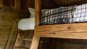 Een houten stapelbed met een ladder, witte kussens en een geruit dekbed.