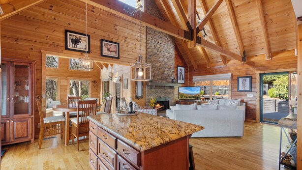 Un salón amplio con un gran techo de madera, una chimenea de piedra y un televisor.