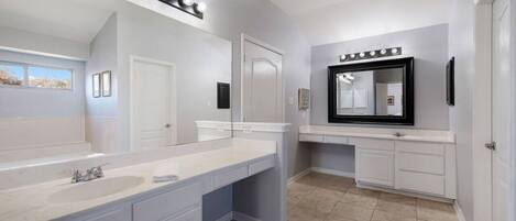 A bathroom with a large mirror, vanity, and a lighted vanity area.