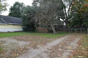 yard with a dirt path leading to a wooden fence and a tree.