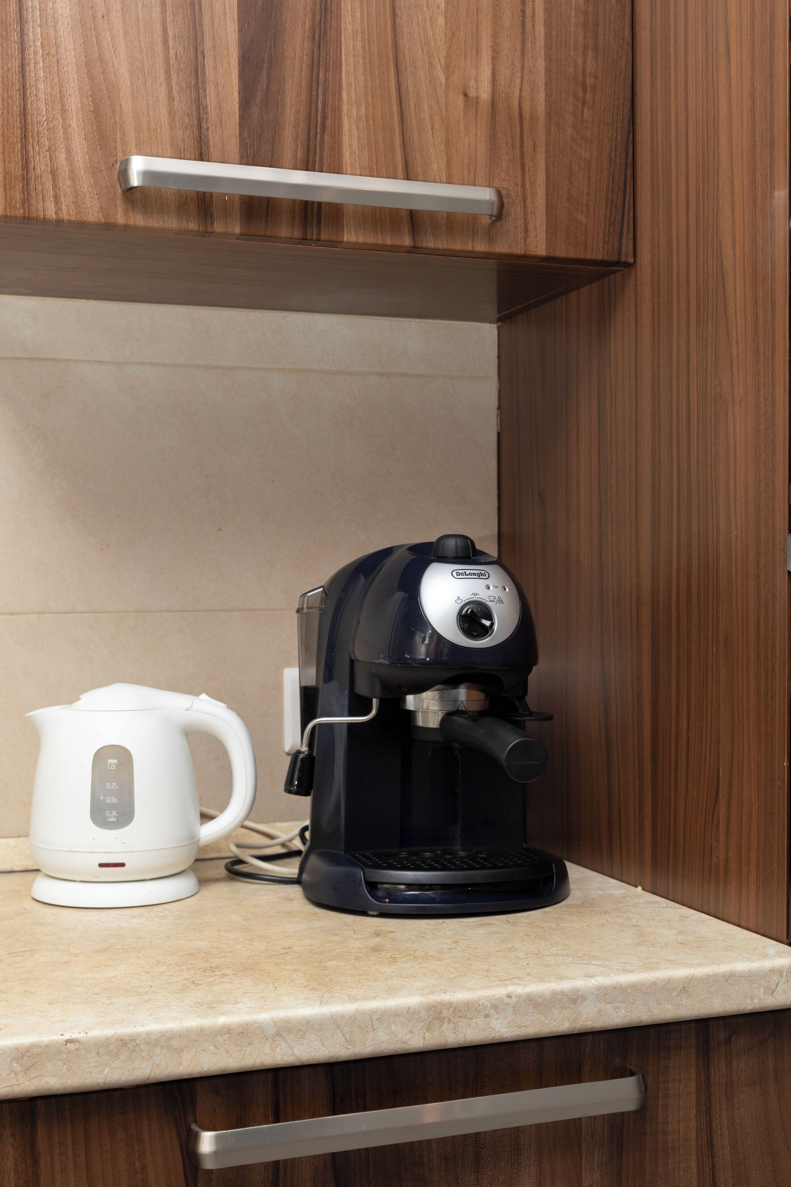 A coffee maker on a kitchen counter with a white kettle beside it.