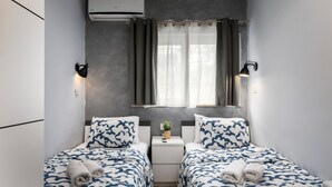 A twin room with two beds, a small bedside table with a plant, and a window with curtains. - Modern Ensuite Rooms Near Balluta Bay (St. Julian's)