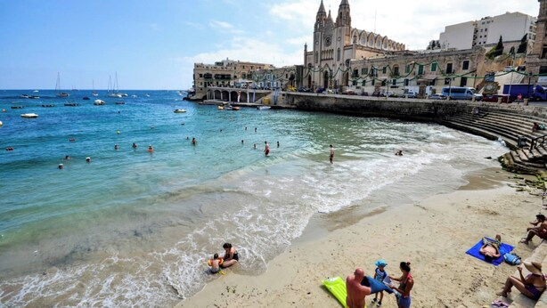 A beach with clear waters, a historic building, and a promenade. - Modern Ensuite Rooms Near Balluta Bay (St. Julian's)