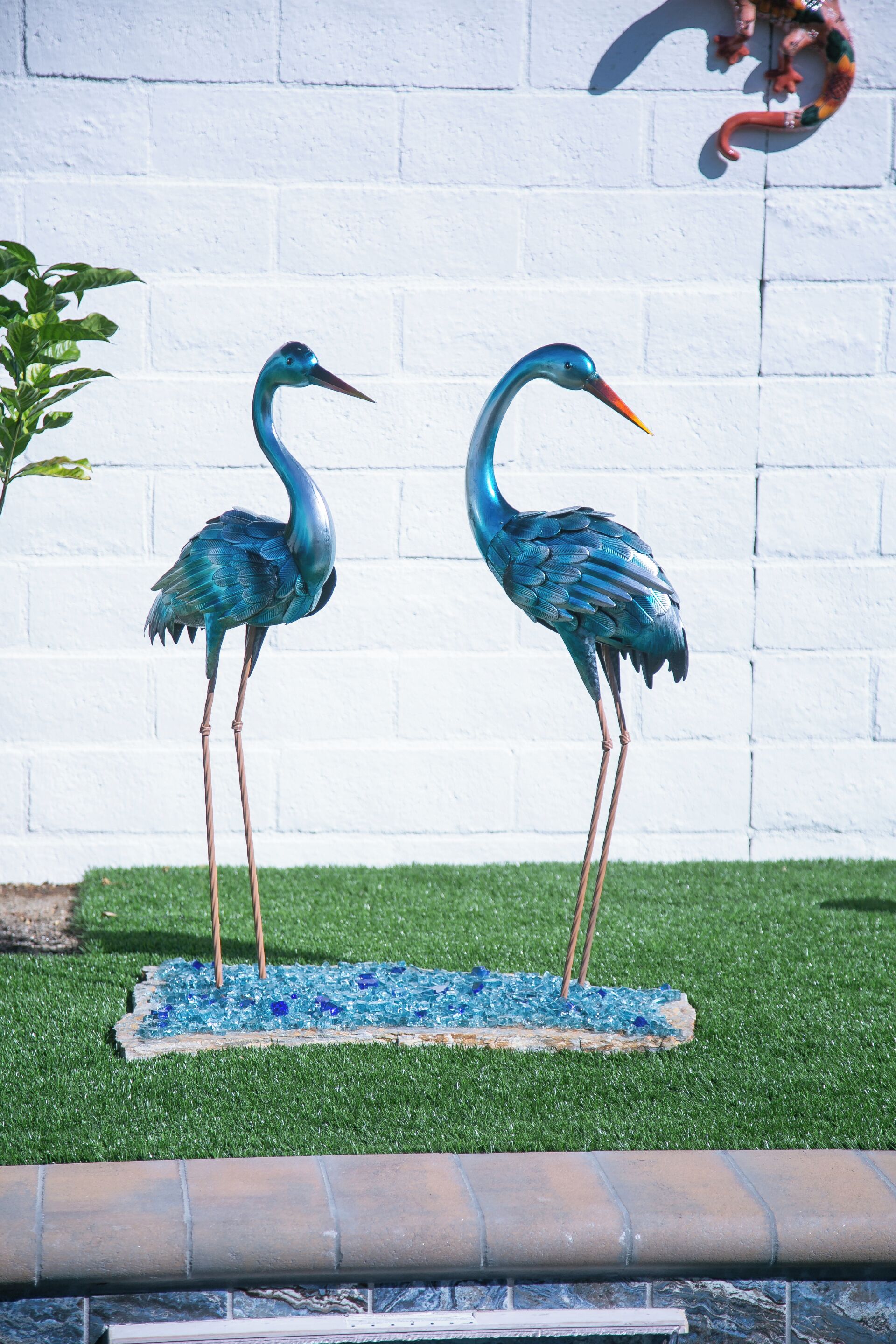 Dos estatuas de garzas azules sobre un pedestal de mosaico azul.