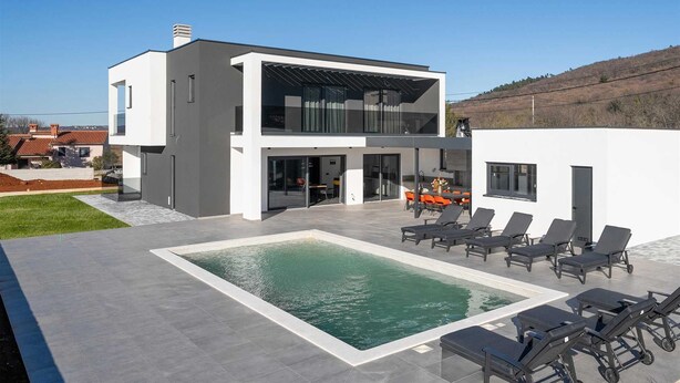 Ein modernes Haus mit zwei Etagen, einem Schwimmbad und einer Sitzgelegenheit im Freien.