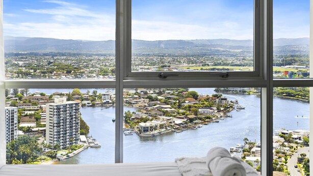 A view from a window overlooking a river with buildings and a distant mountain range.