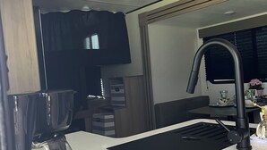 Una kitchenette compacta con un lavamanos, una cafetera y una ventana.