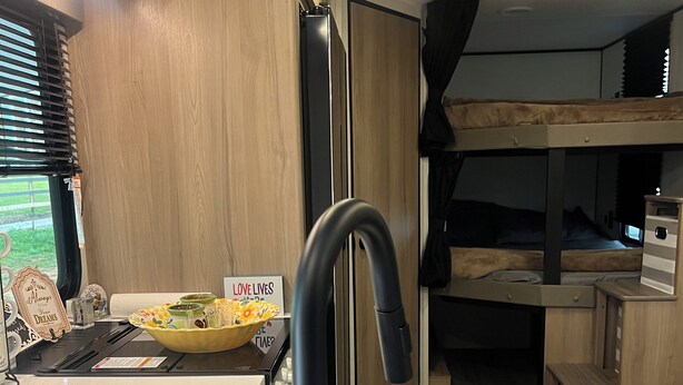 Una cocina moderna con un grifo negro, un lavamanos y una encimera. Hay un letrero que dice “LOVE LIVES” y un bol con condimentos.