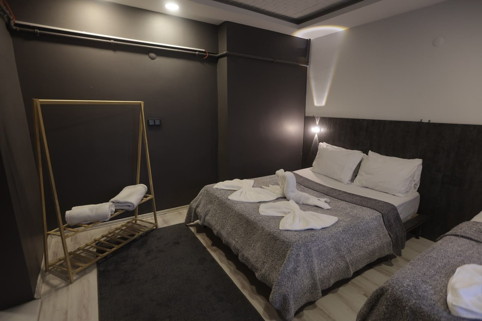 Una habitación de hotel con una cama, un banco y un perchero.
