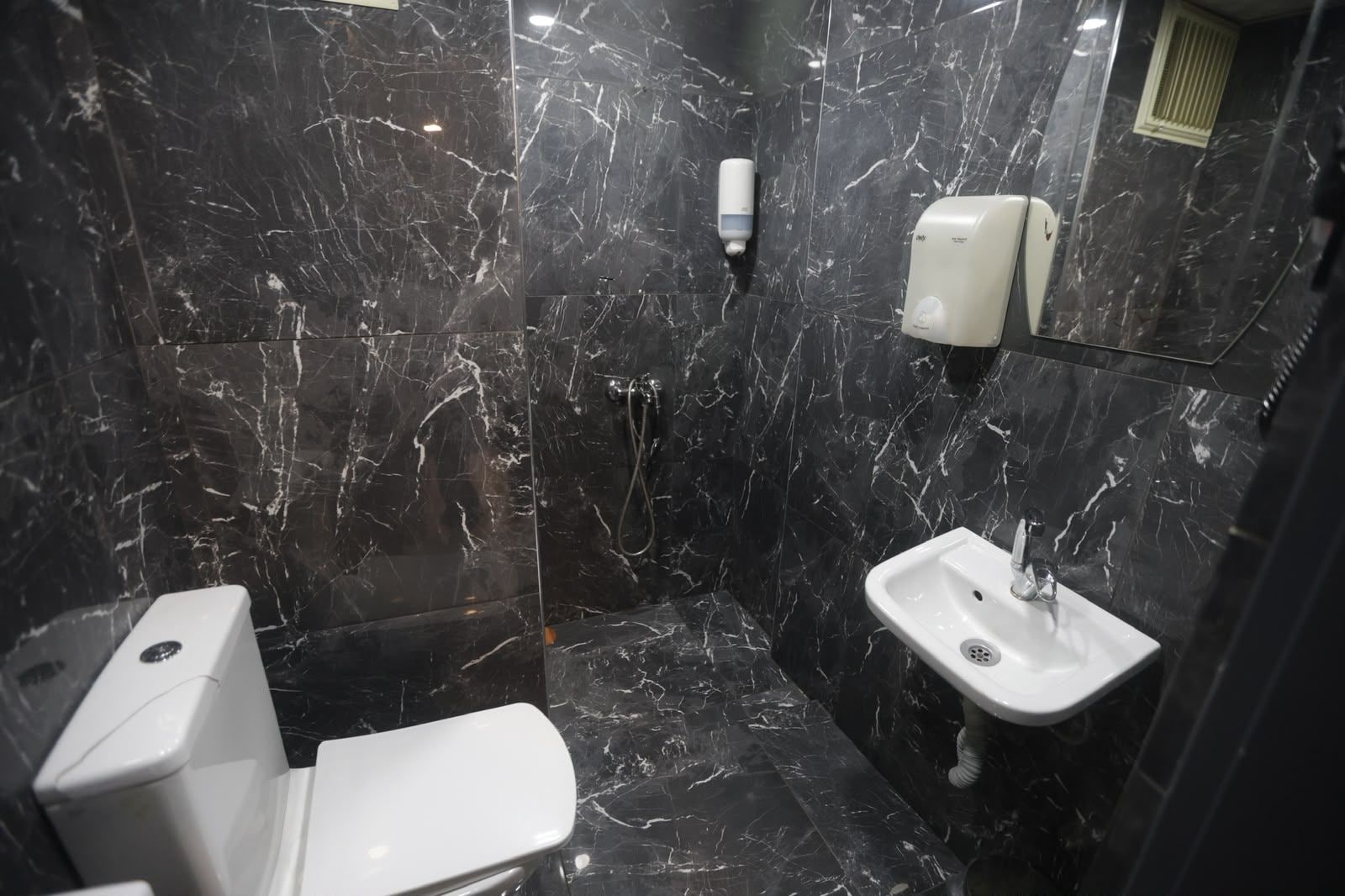Un baño con inodoro, lavamanos y zona de ducha.