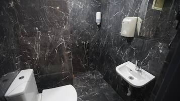 Un baño con inodoro, lavamanos y zona de ducha.
