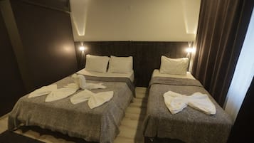 A hotel room with two beds, each with a grey blanket and white towels.