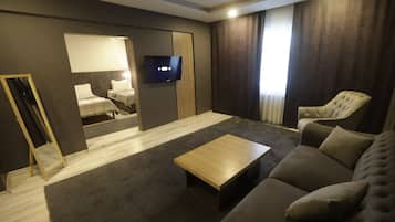 A modern living room with a sofa, a coffee table, a TV, and a bed with a mirror.