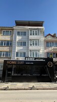 Un edificio con un letrero que indica 'HOME SUIT APART & OTEL', mostrando un servicio de alquiler de apartamentos y oficinas.