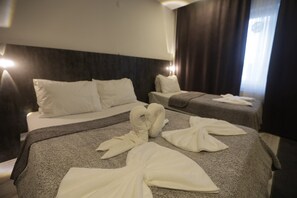 A hotel room with two beds, each with white linens and a dark headboard. - Home Suit apart otel (Kutahya)